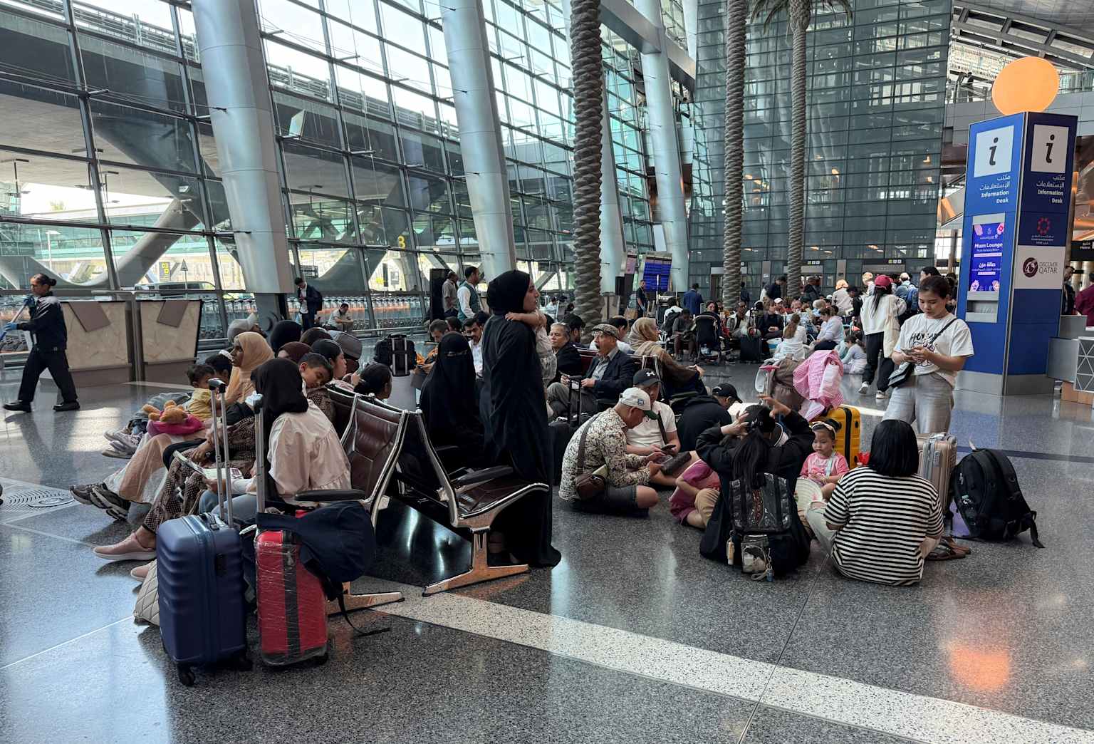 Passengers stranded and waiting at a busy airport terminal amid flight disruptions.