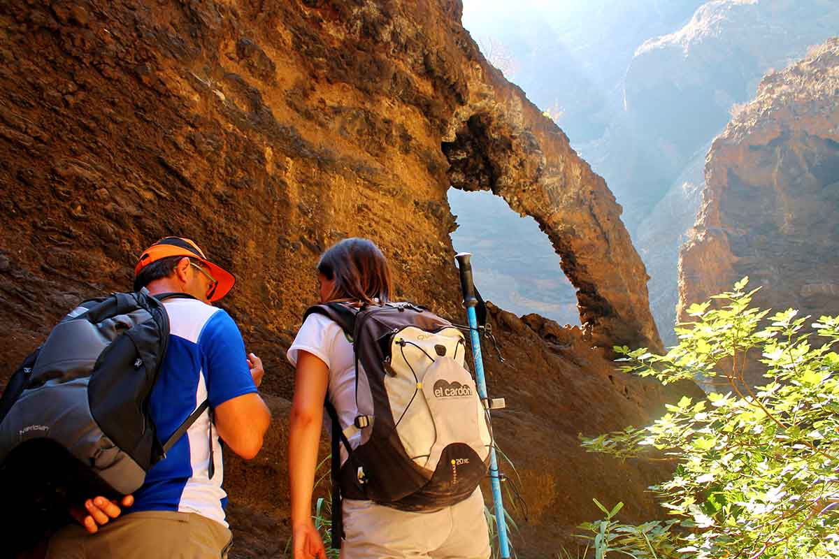 Hikers exploring the dramatic Masca Gorge canyon cliffs on Tenerife's popular hiking trail.